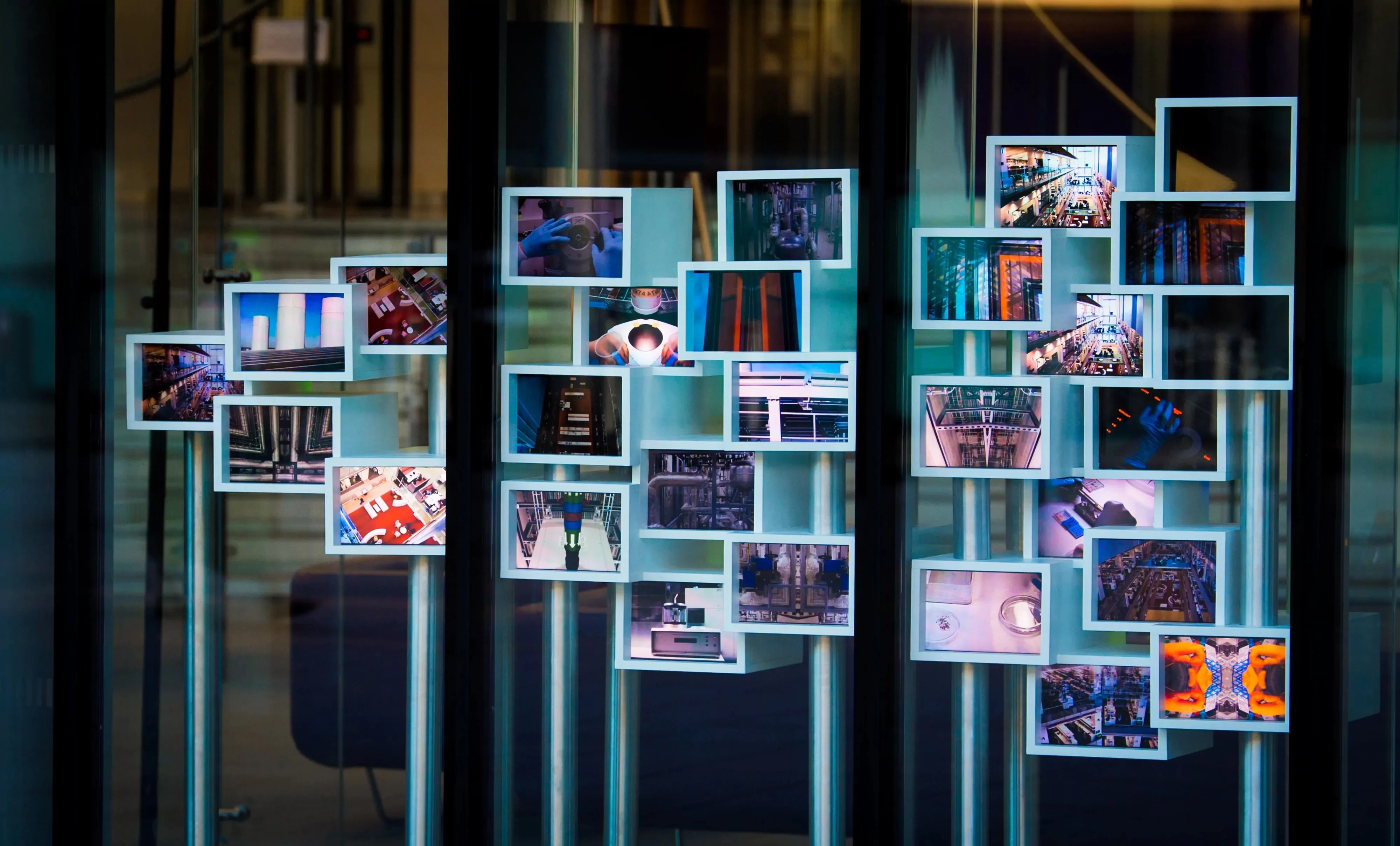 Installation view of Flow State in the front window of the Francis Crick Institute showing branching clusters of synchronised screens.